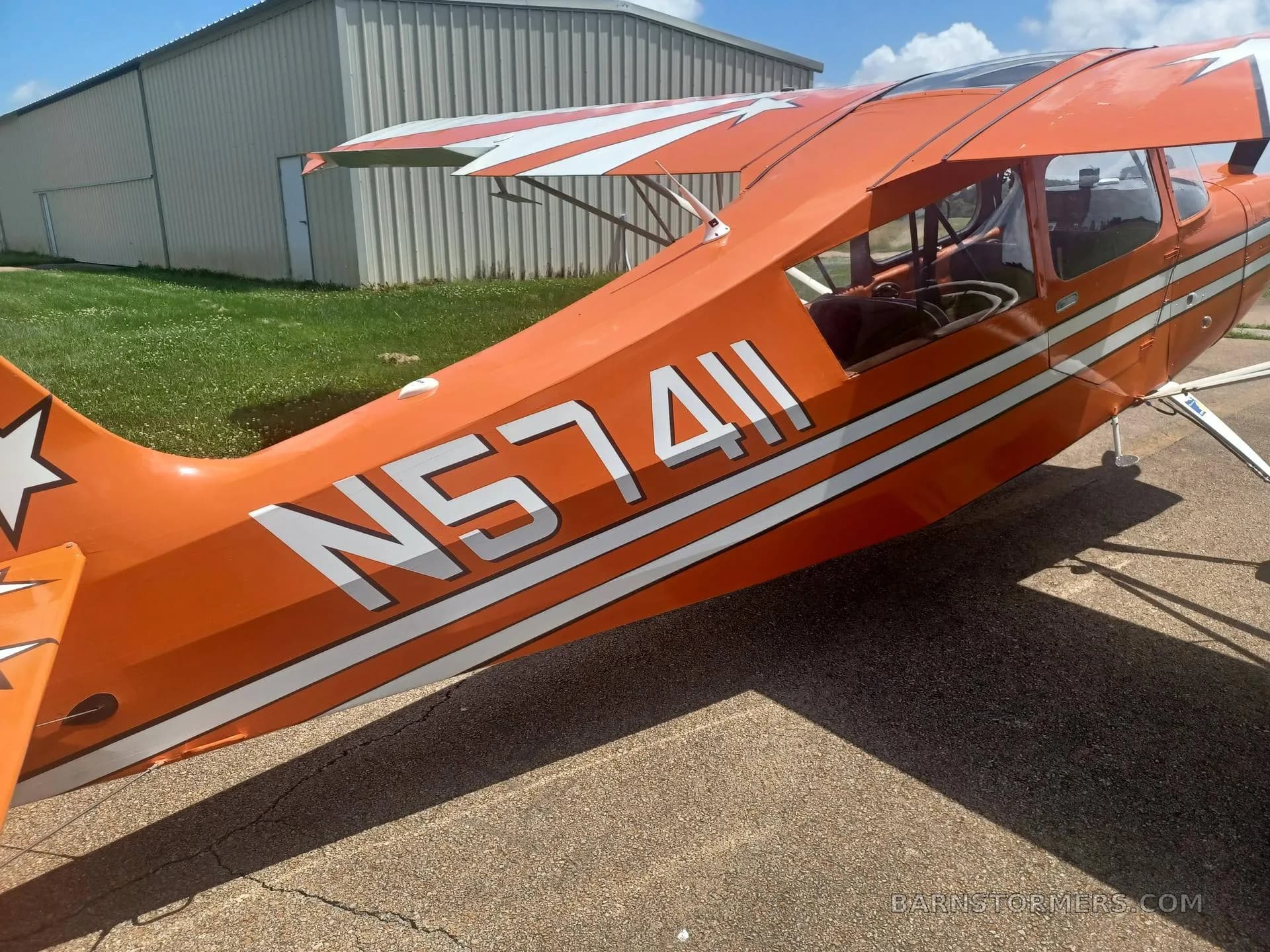 A close-up view of the rear fuselage and tail of the orange and white aircraft, clearly showing registration N57411.