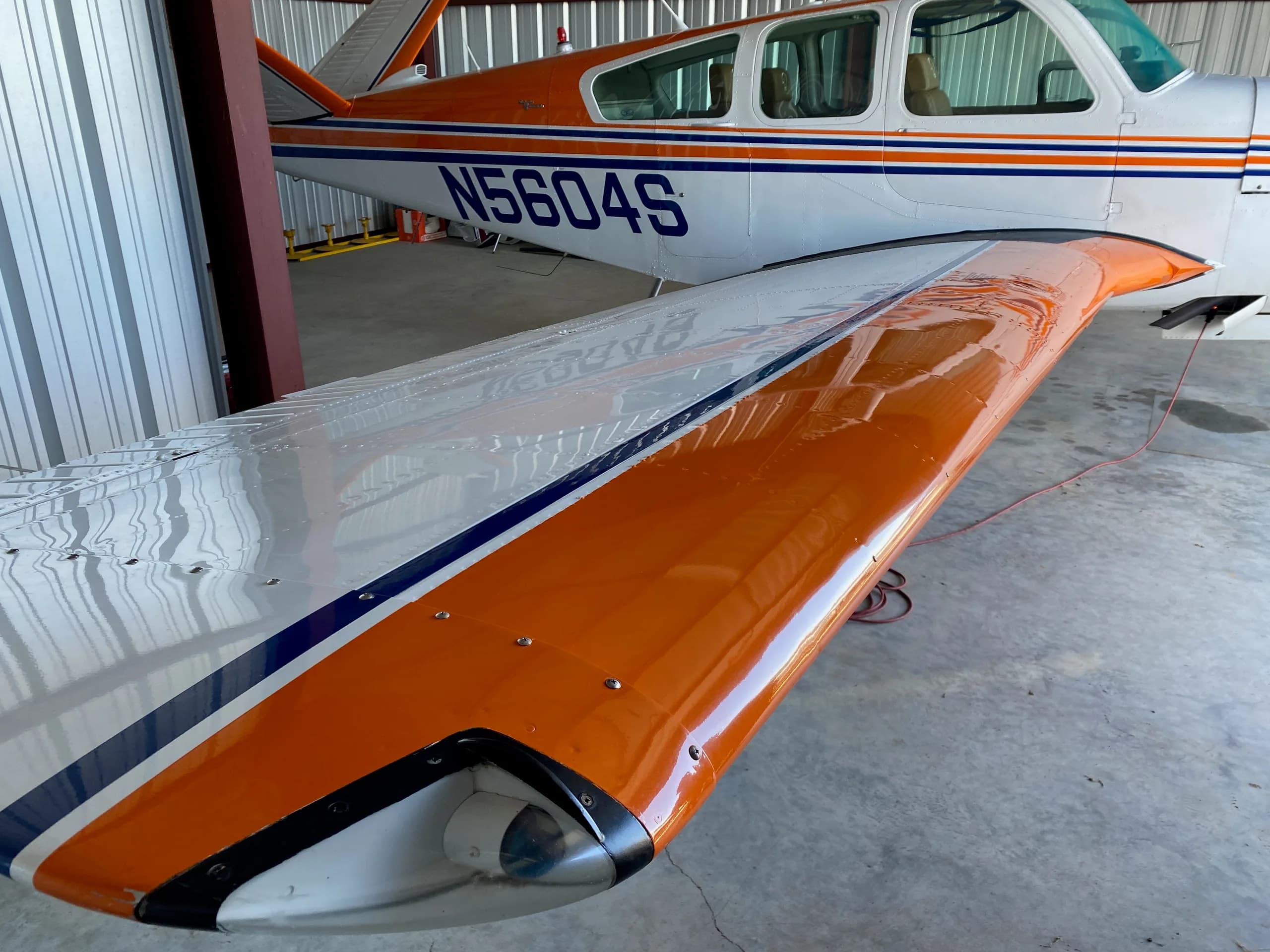 Close-up of the wing and tail of a Beechcraft V35 Bonanza aircraft with registration N5604S.