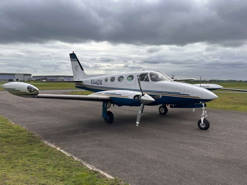 A Cessna 414 Chancellor aircraft on the tarmac with a white and blue paint scheme.