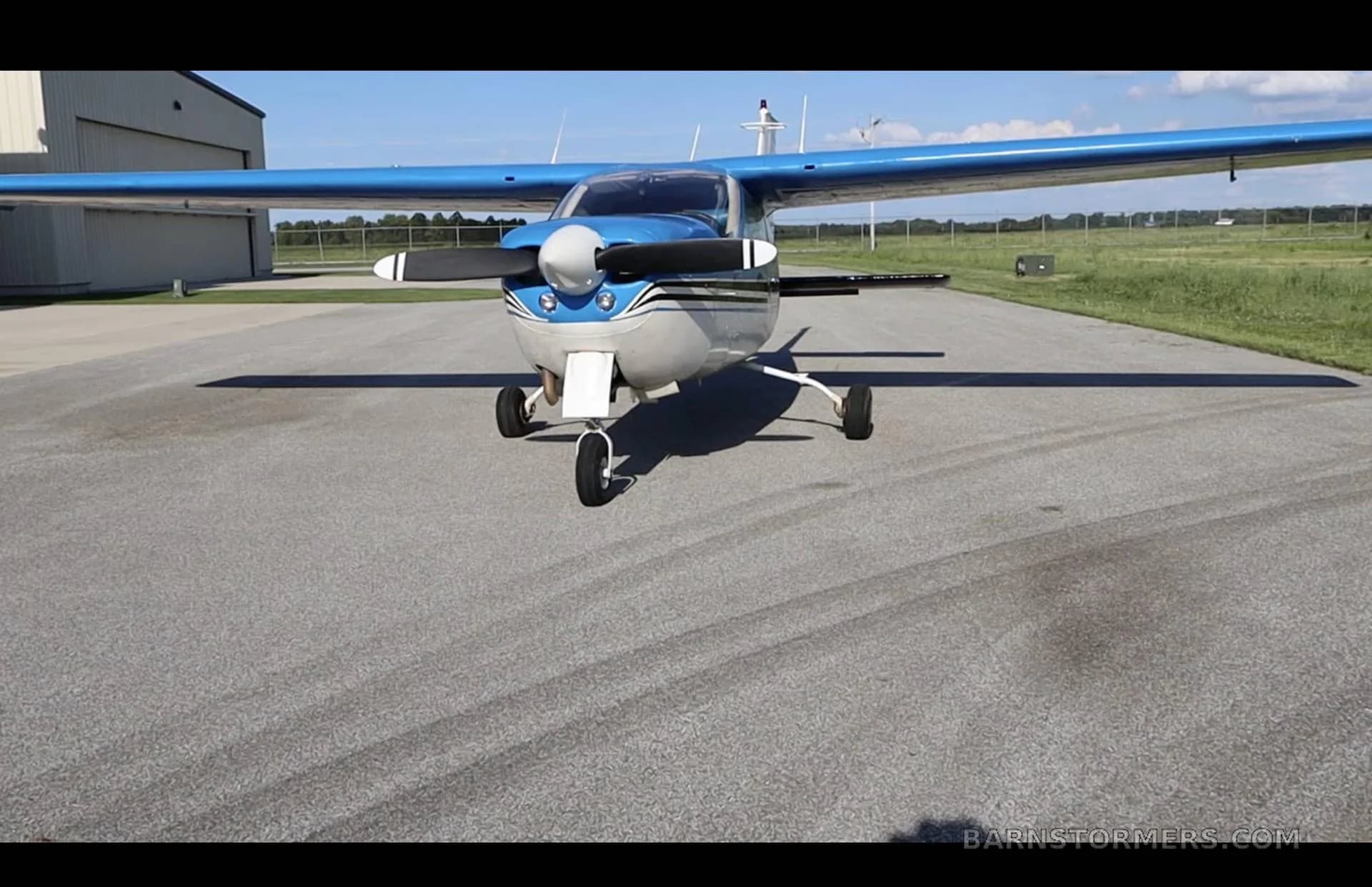 A front view of a blue and white Cessna 210 Centurion with registration N2014Q parked on an asphalt ramp.