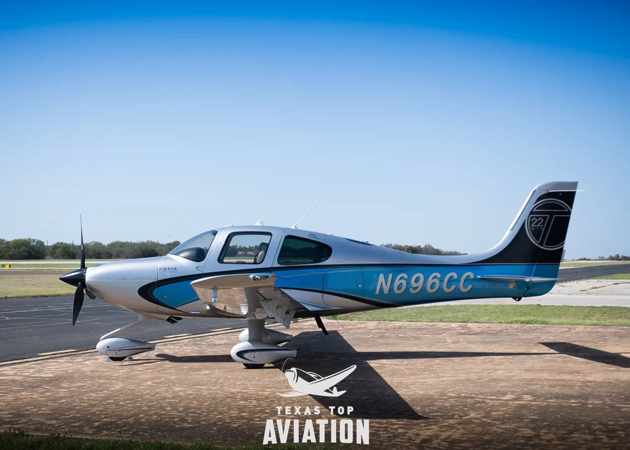 A Cirrus SR22 aircraft with blue and silver paint scheme, displaying N696CC, parked on an airfield.