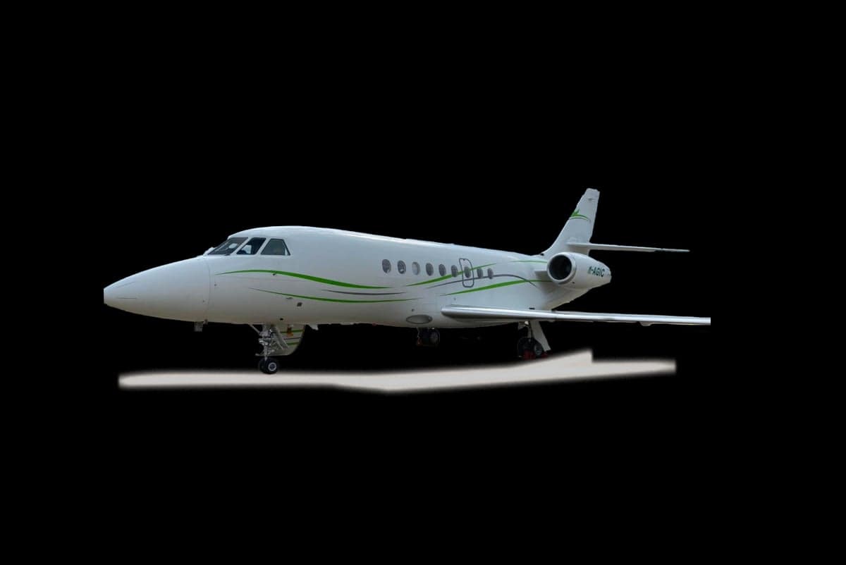 A white Dassault Falcon aircraft with green accents on a black background.