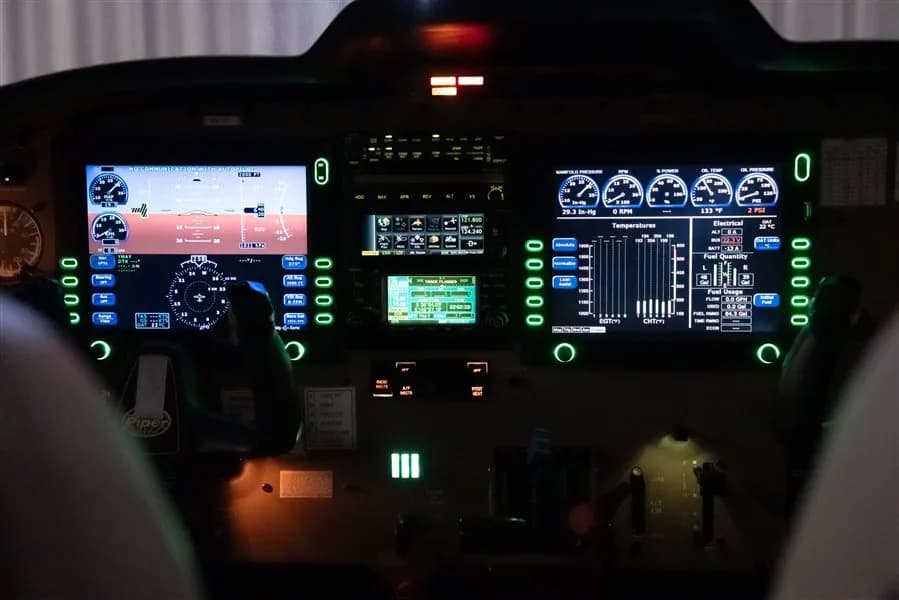 An illuminated aircraft cockpit with multiple digital displays showing flight and engine information.