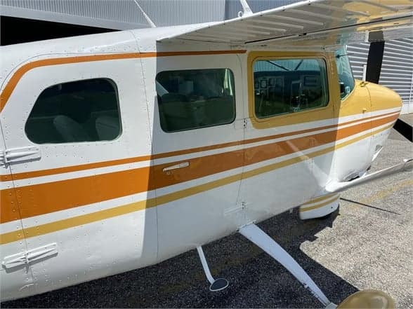 Side view of a Cessna 210 Centurion aircraft showing the cabin windows and paint scheme.