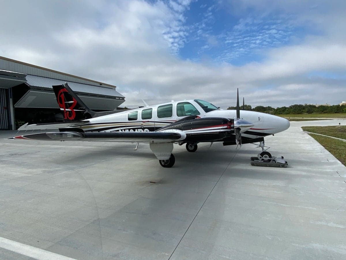 A side view of a white and black twin-engine aircraft with registration N581PS, parked on an airfield.