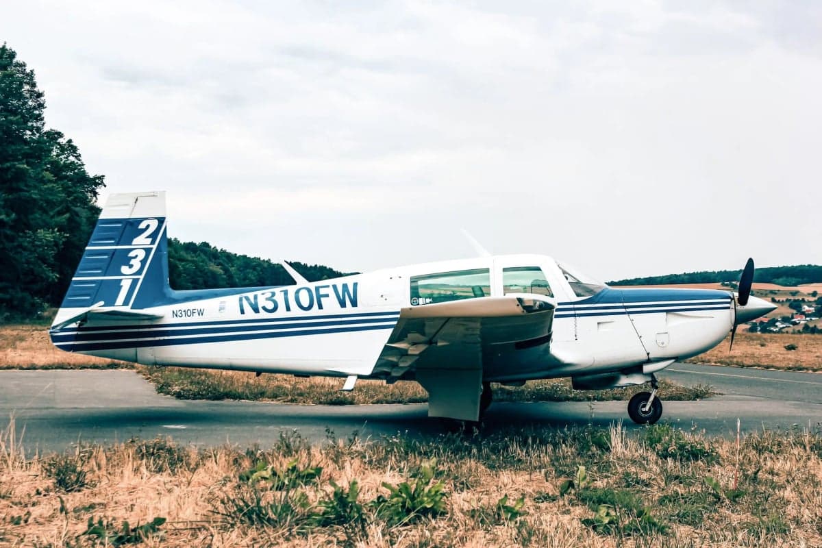 N310FW parked on a runway with grass in the foreground.