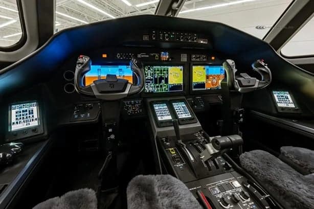 A view of the jet's cockpit with multiple screens and controls.