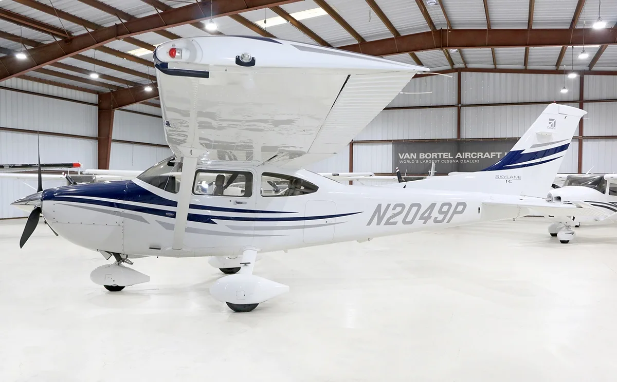Right side view of a white and blue Cessna Skylane TC (N2049P) in a hangar.