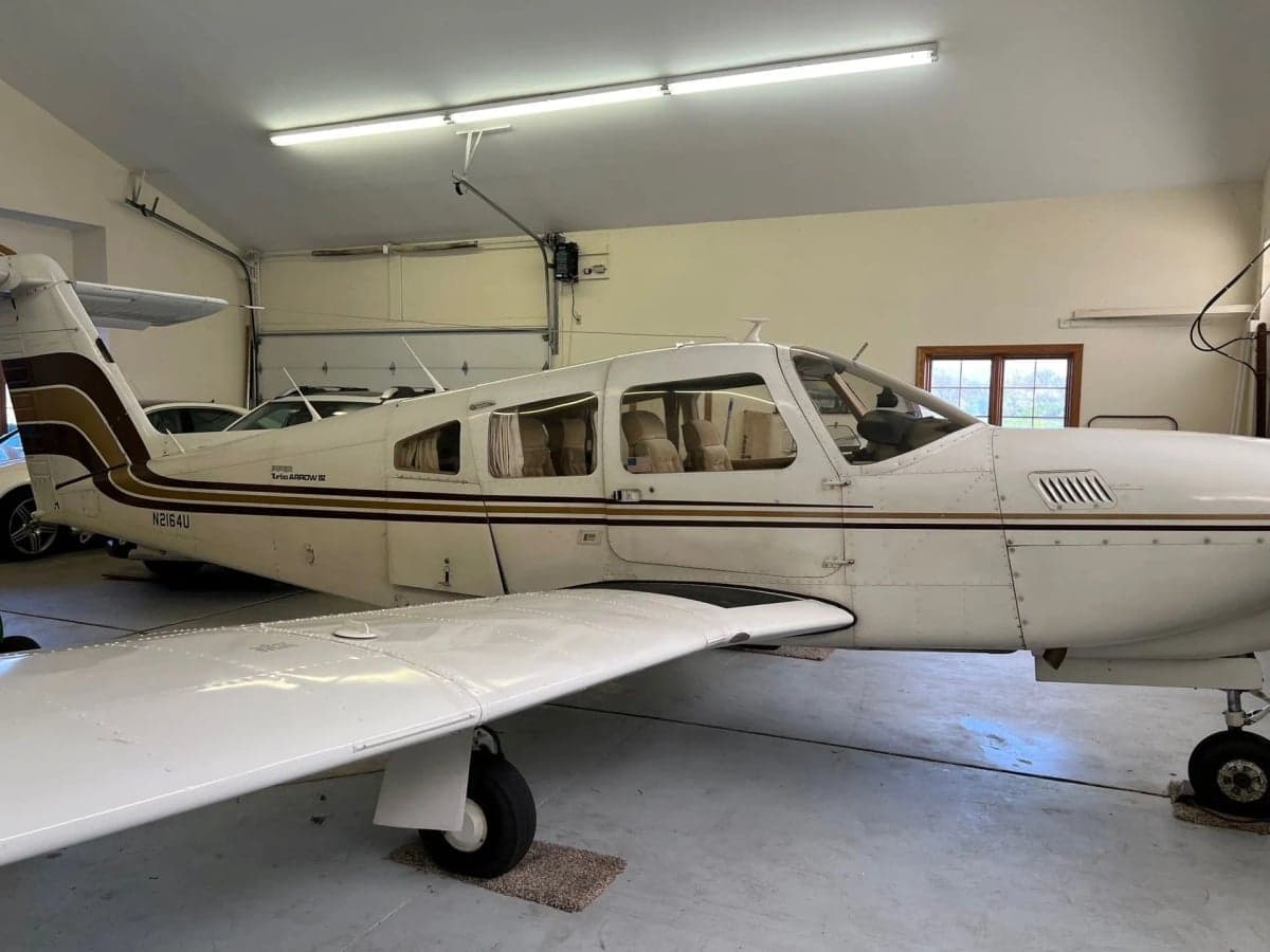 A Piper Turbo Arrow III aircraft parked inside a hangar.