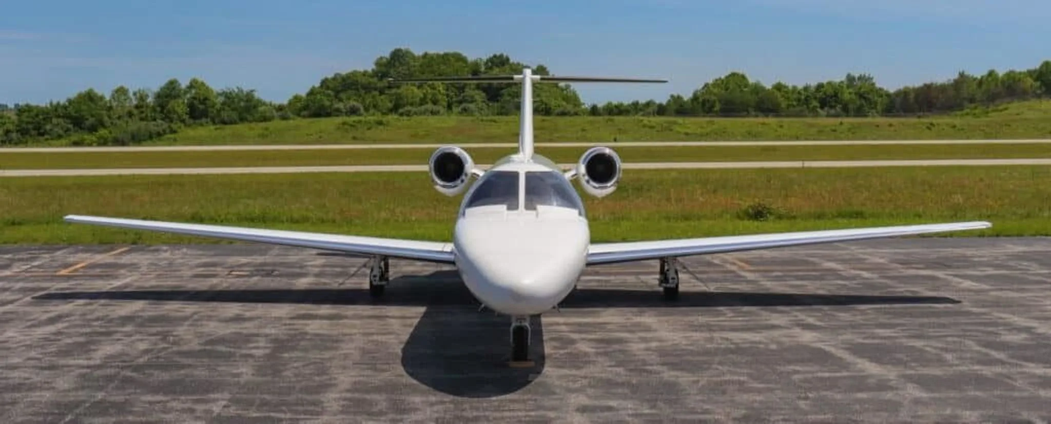 A head-on view of a white Cessna Citation CJ2+ business jet parked on an airfield.