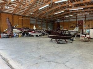 Several helicopters are parked inside a hangar.