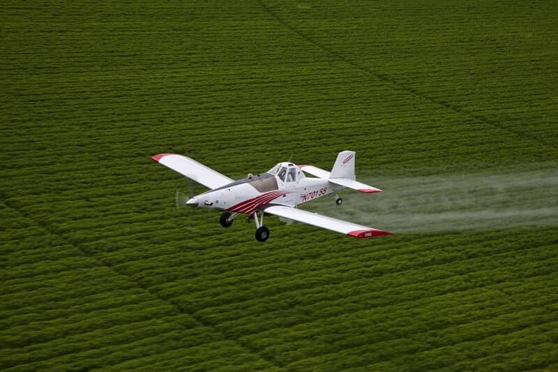 A Thrush aircraft spraying crops over a field.