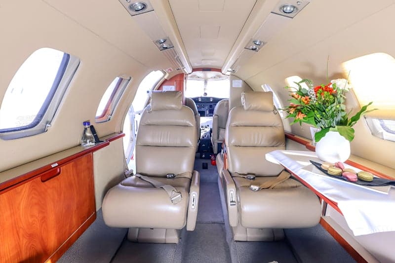 Interior of the aircraft with leather seats and a table with flowers.