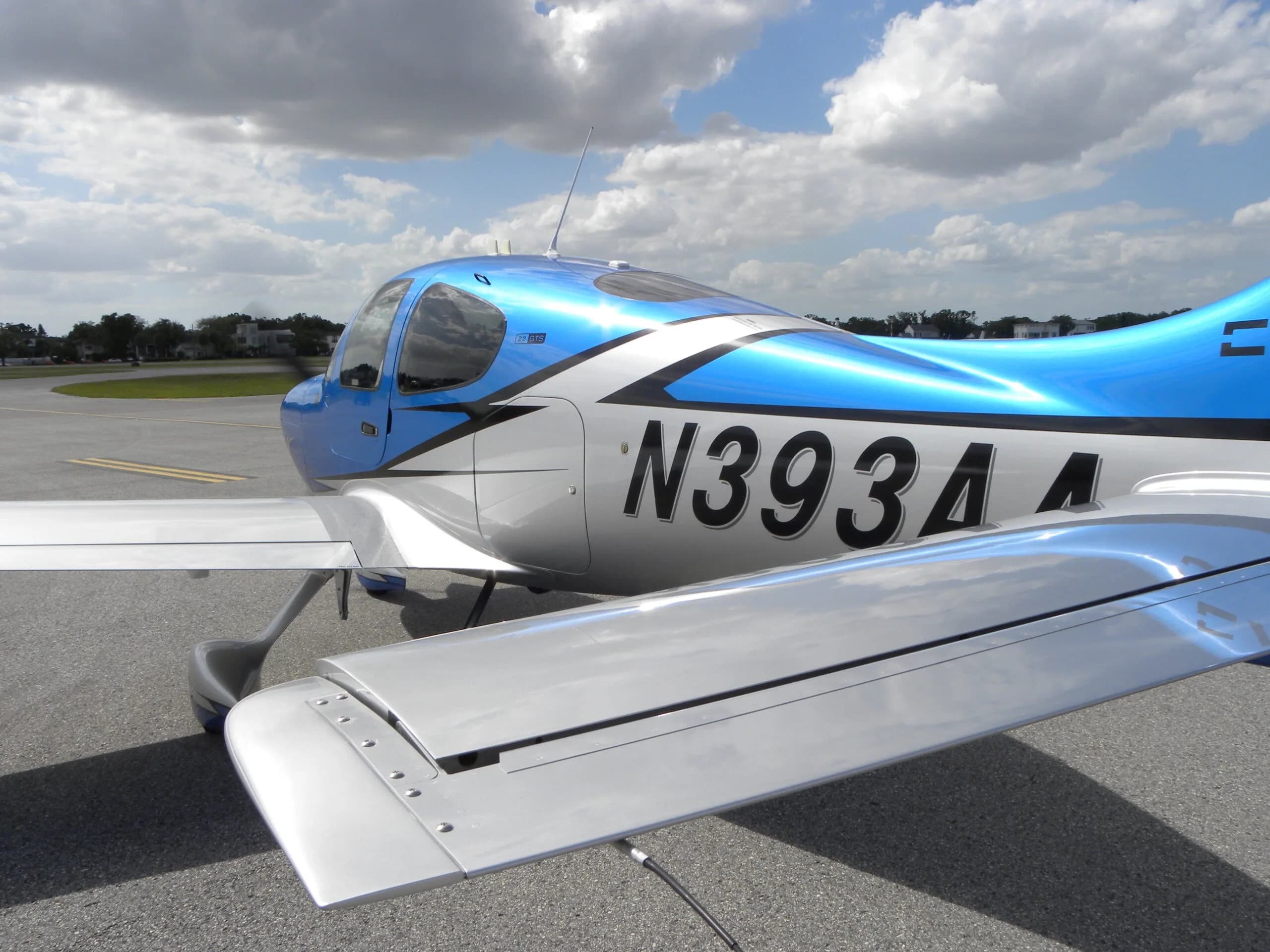 A close-up view of the rear fuselage and wing of a blue and silver Cirrus SR22 aircraft with registration N393AA.