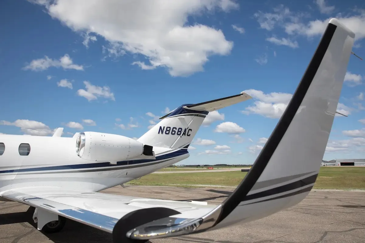 A close-up view of the tail section of the Cessna Citation CJ1+ (N868AC) with blue and grey stripes.