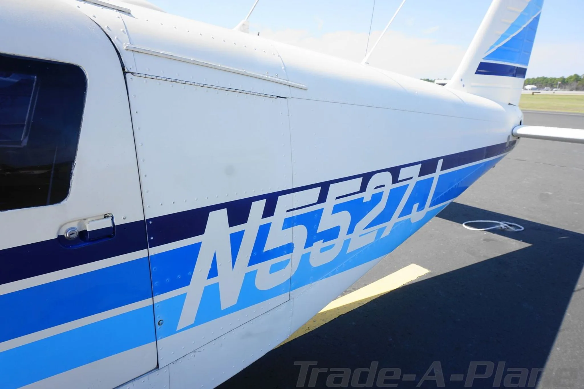 Close-up of the N5527J aircraft fuselage showing the blue stripe paint scheme.