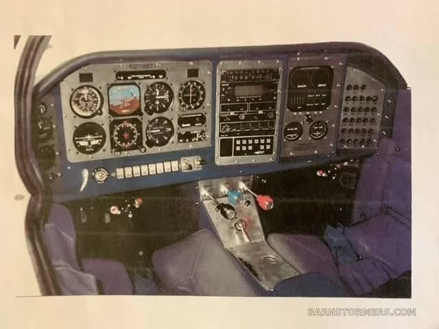 The instrument panel and controls of an aircraft (N210ST) with analog gauges and avionics are shown, captured from a printed photo.