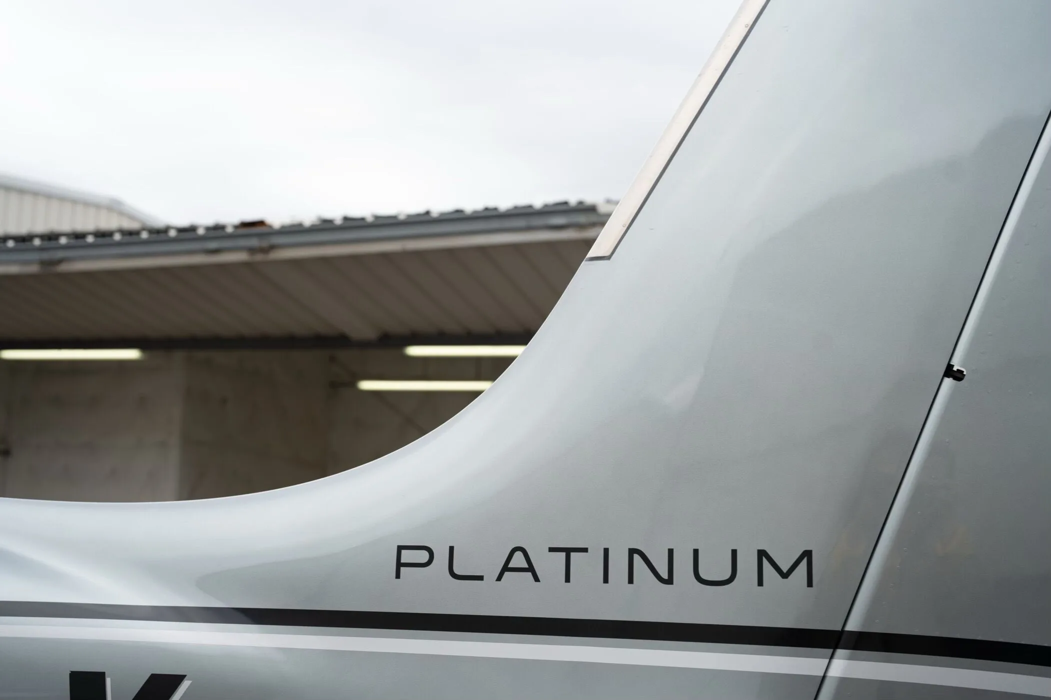 A close-up view of the "PLATINUM" designation on the tail of the silver Cirrus SR22 GTS aircraft.