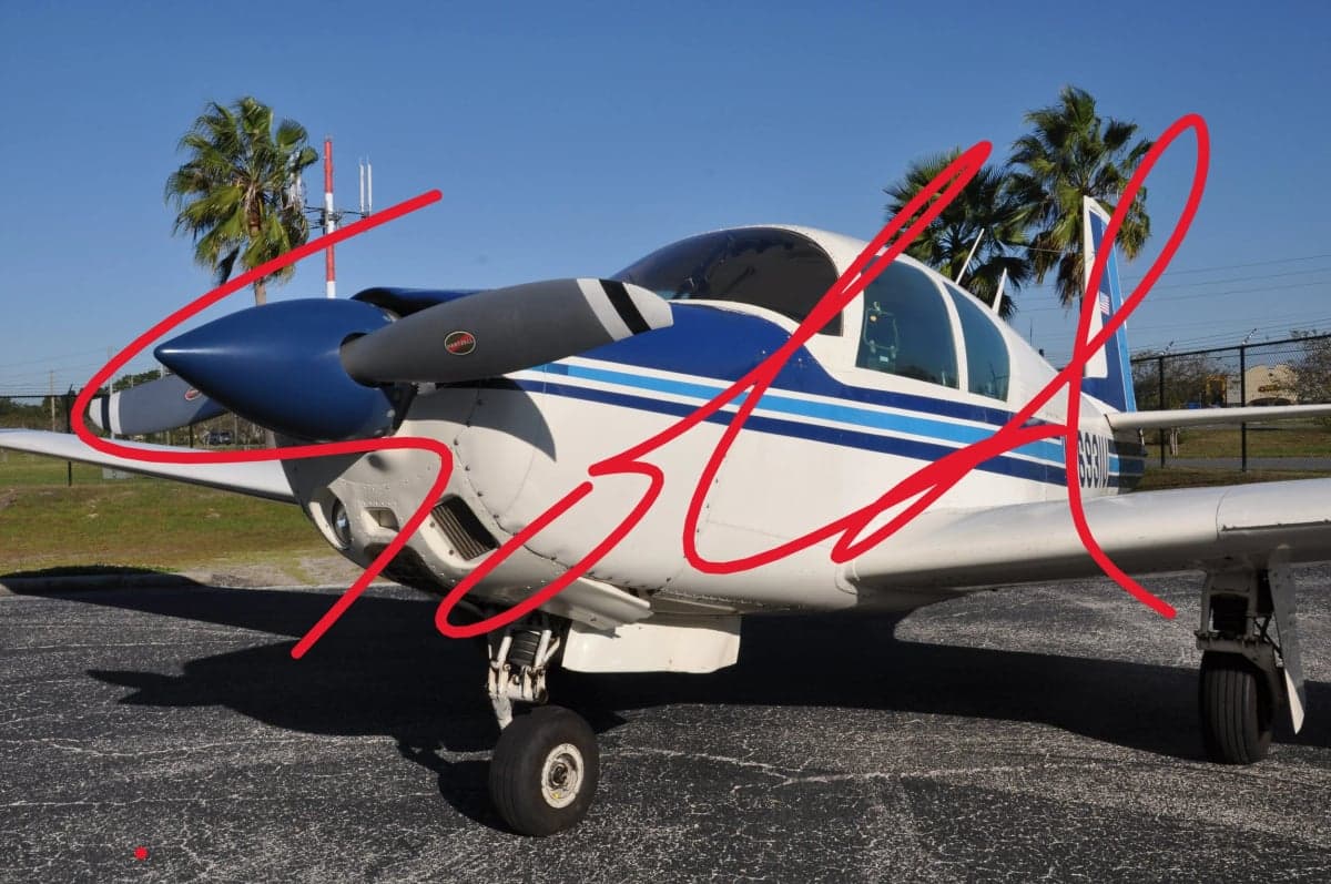 Close-up of a white and blue Mooney aircraft with the word SOLD overlaid.