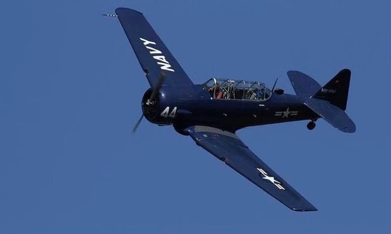 A blue North American T-6 Texan aircraft in flight.