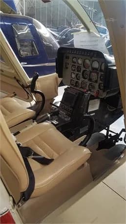 Cockpit view of the helicopter with beige seats and instrument panel.