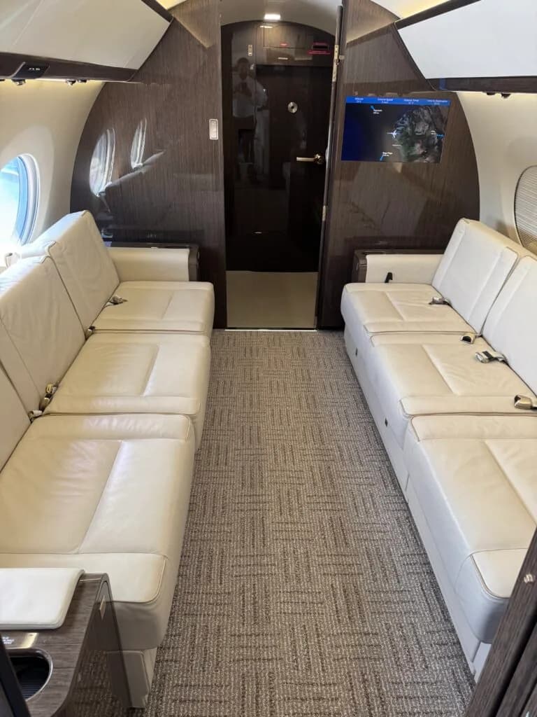 The aft section of the Gulfstream cabin, featuring two long, light-colored leather divans facing each other.