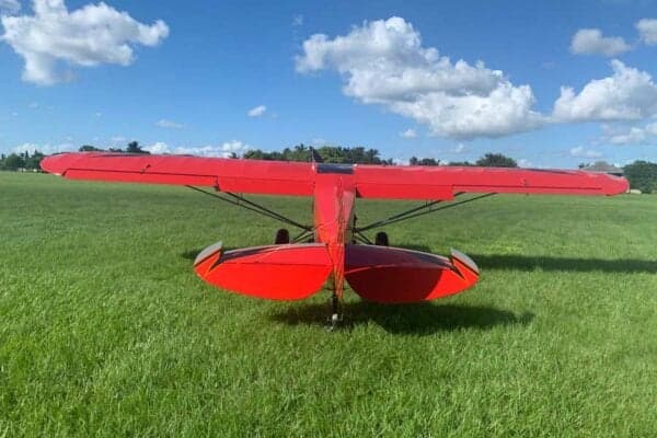 Rear view of the red Legend Cub aircraft on the grass.