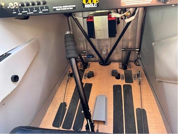 View of the rudder pedals, control stick, and lower instrument panel area of the N90LC Legend Cub cockpit.