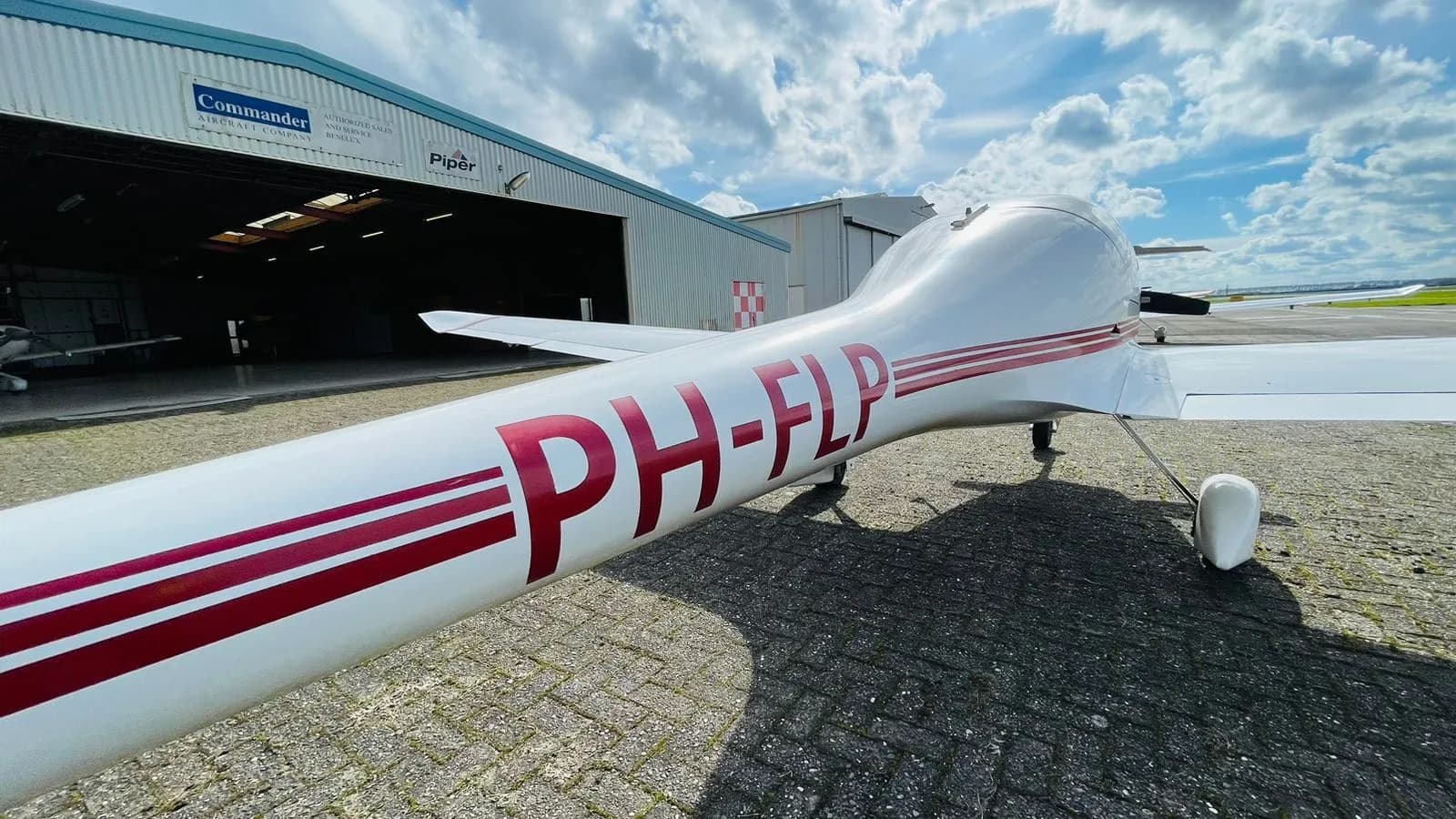 Diamond DV20 Katana aircraft with registration PH-FLP parked near a hangar.