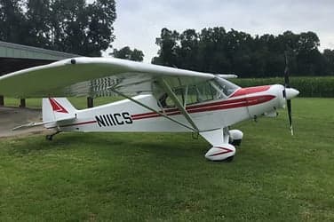 A Piper Super Cub on a grassy field.