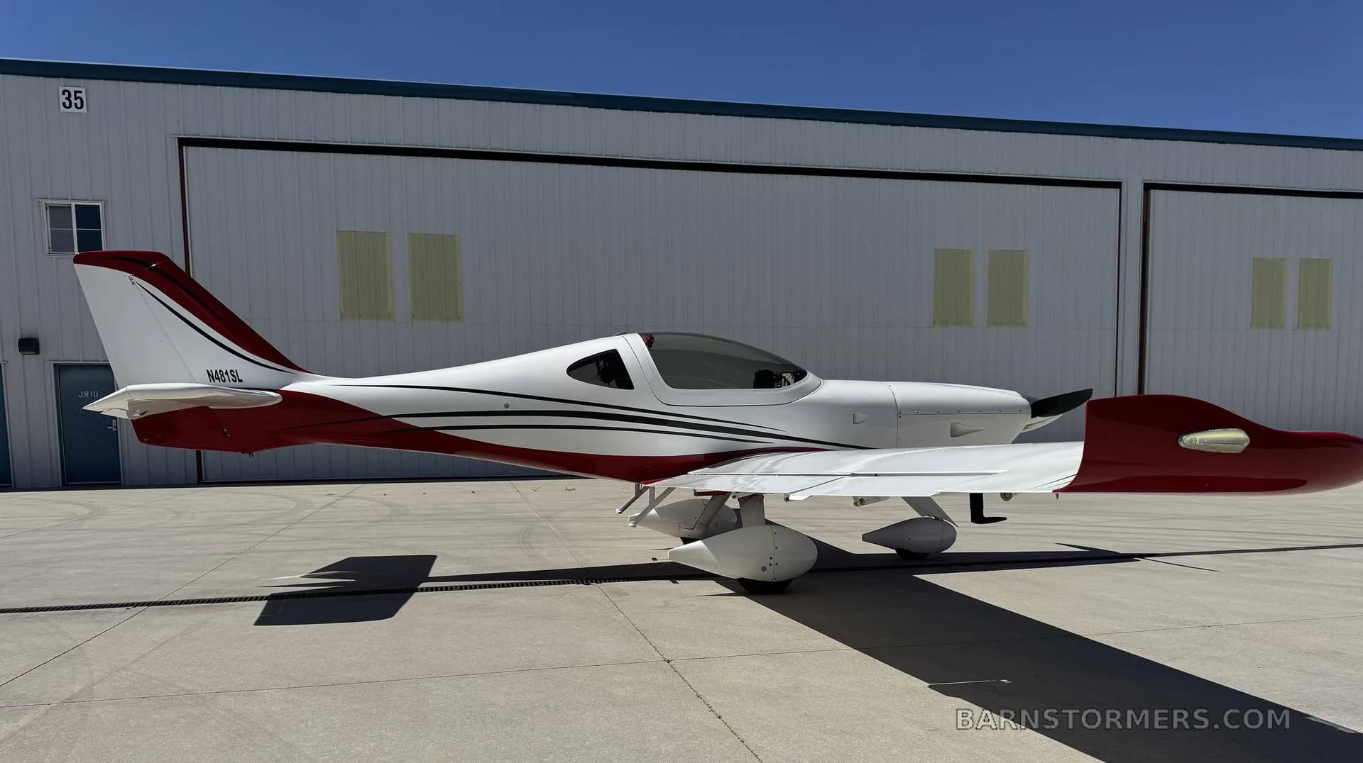 A white and red single-engine aircraft with tail number N481SL, seen from the side on an airfield.