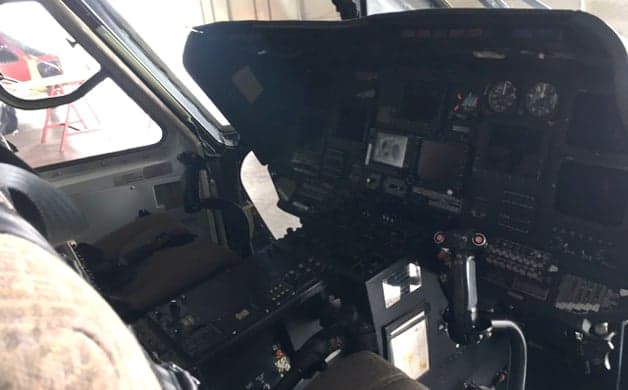 The cockpit of a helicopter with multiple screens and control panels.