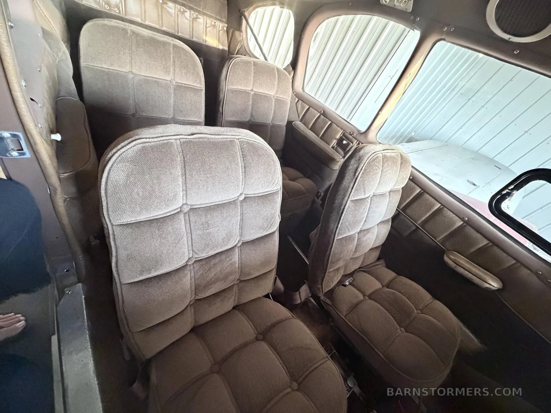 The brown upholstered passenger seats in the cabin of a small aircraft.