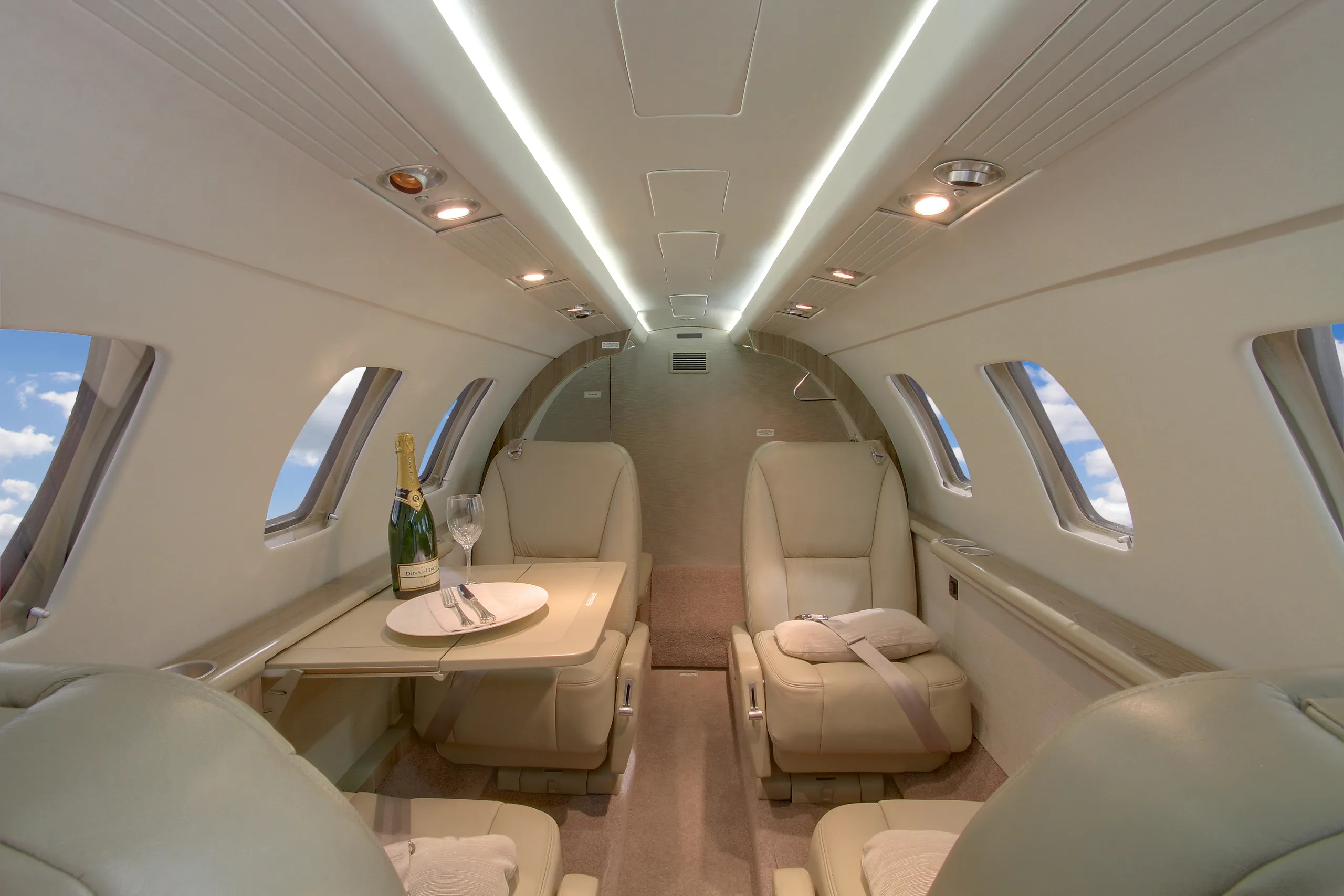 The interior of a Cessna Citation CJ3 features a table with champagne and glasses.
