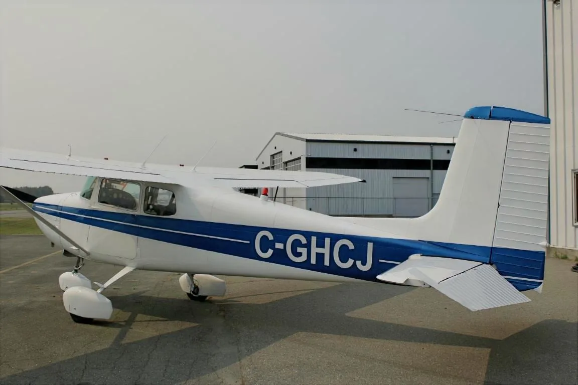 Rear view of a Cessna 172 with blue stripe parked on the tarmac.