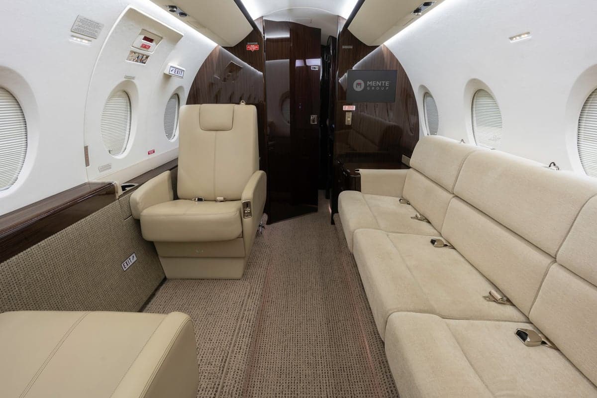 Interior view of the Gulfstream jet cabin with a leather seat and a couch.