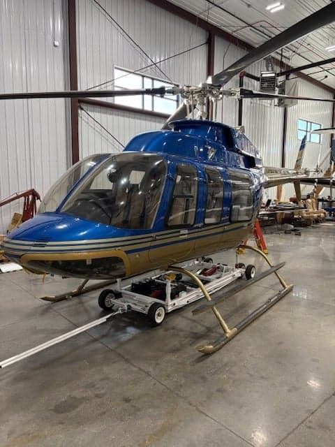 A blue and gold helicopter is shown in a hangar.