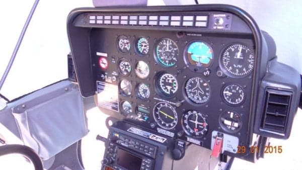 The instrument panel of a helicopter, featuring multiple analog gauges and a radio stack.