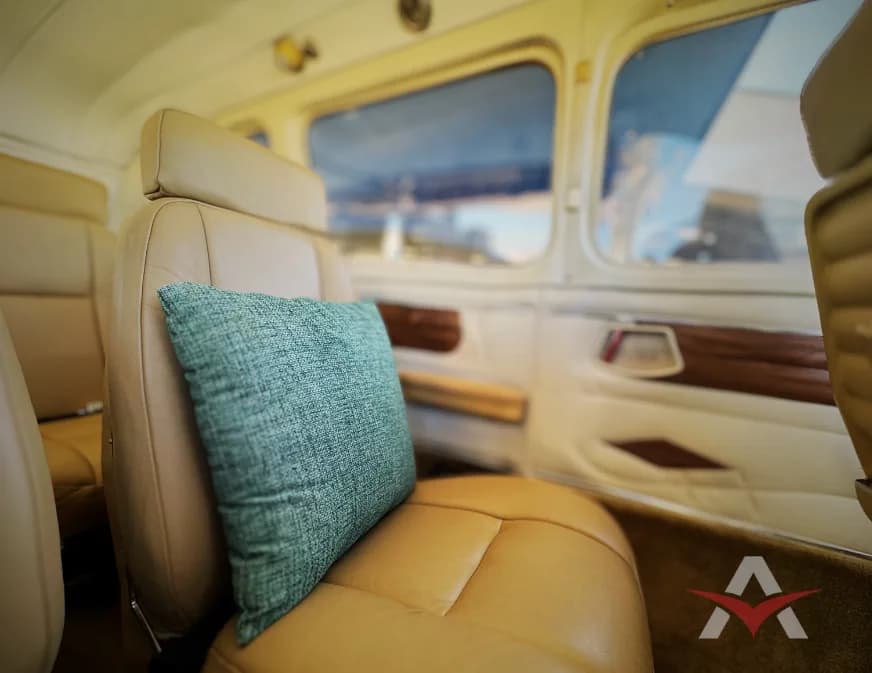 Close-up of a tan leather aircraft seat with a green pillow.
