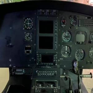 Helicopter cockpit with gray seats and black instrument panel.