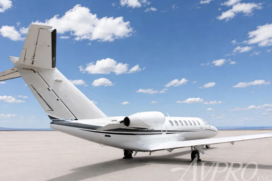 A rear-left view of a white Cessna Citation jet showing the tail and engine.