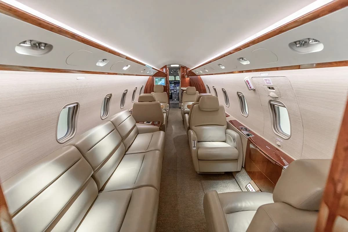 A view of the Challenger 350 cabin with beige leather seats and a couch from the front.