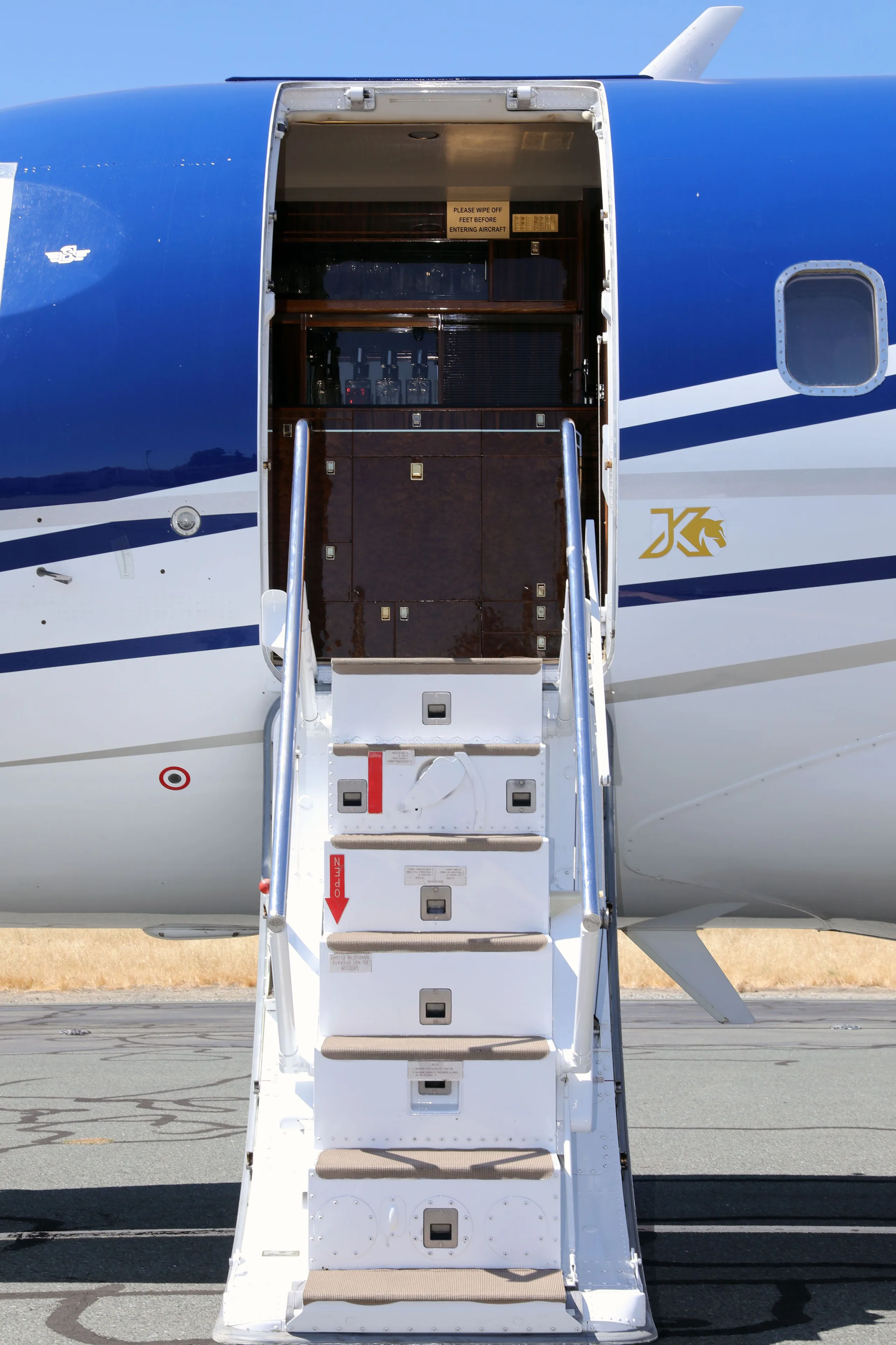 The open main cabin door and integrated airstairs of the blue and white Bombardier Challenger 604 aircraft.