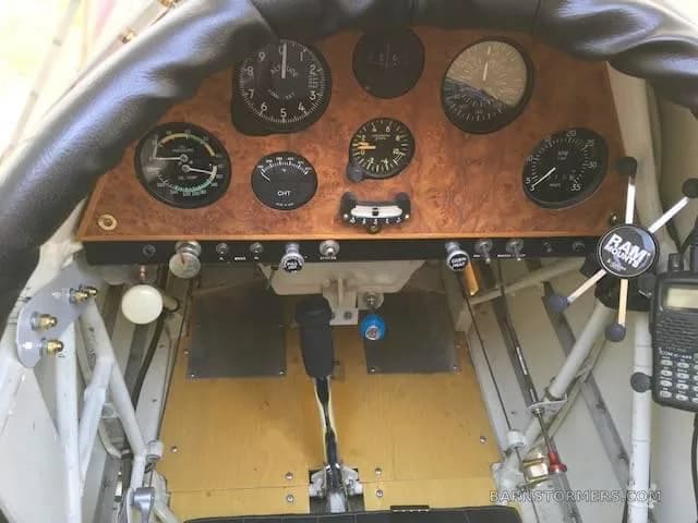 A close-up view of a vintage aircraft cockpit with a wooden instrument panel, gauges, and controls.