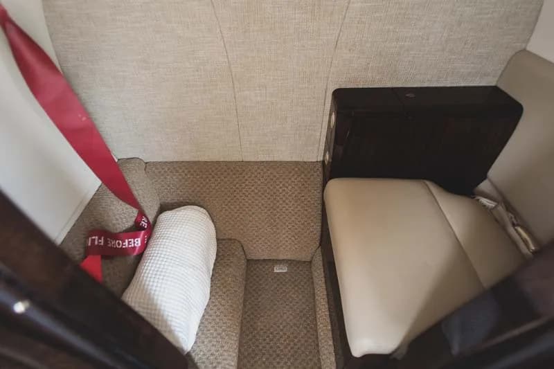 View of the aircraft's interior with a seat, side table, and carpeted floor.