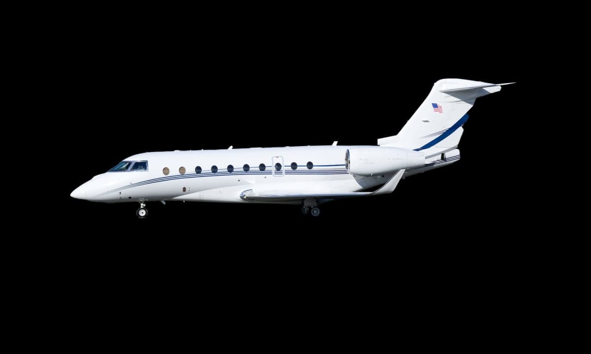 A white Gulfstream jet with blue stripes is shown against a black background.
