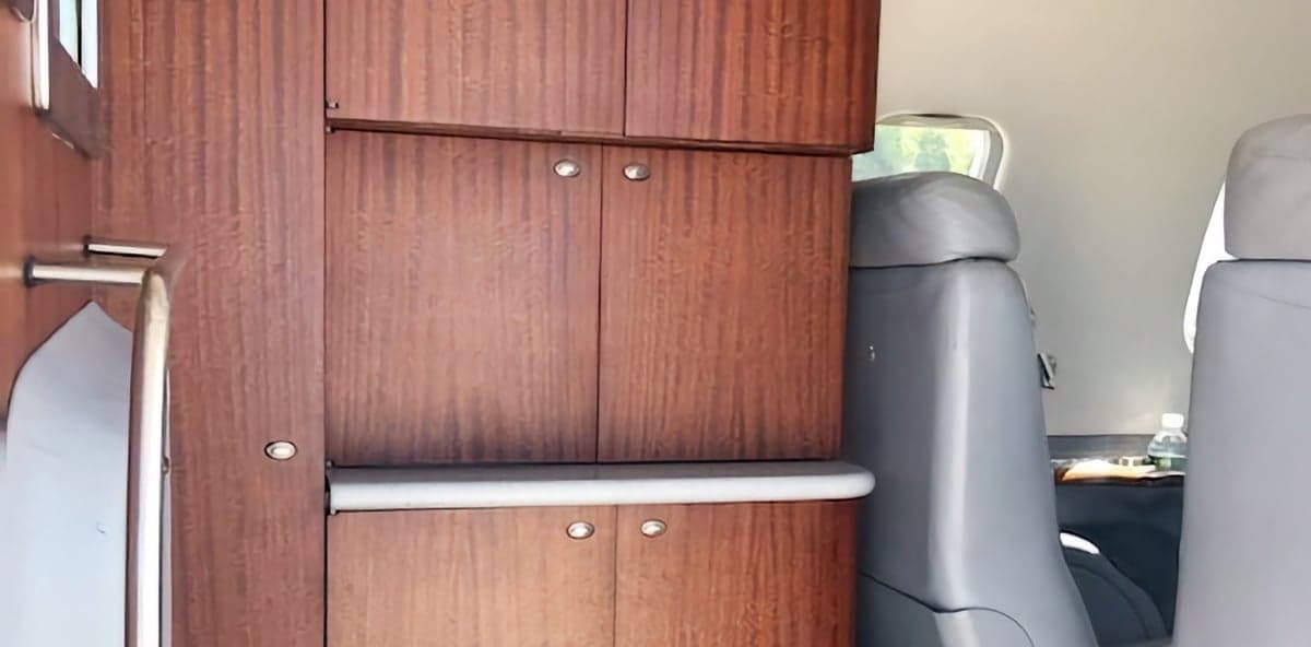Aircraft cabin with wood cabinetry and gray leather seats.