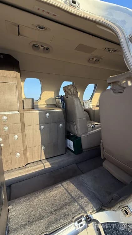 The interior cabin of a private jet showing the entry area with wood-paneled cabinetry and a side-facing seat.
