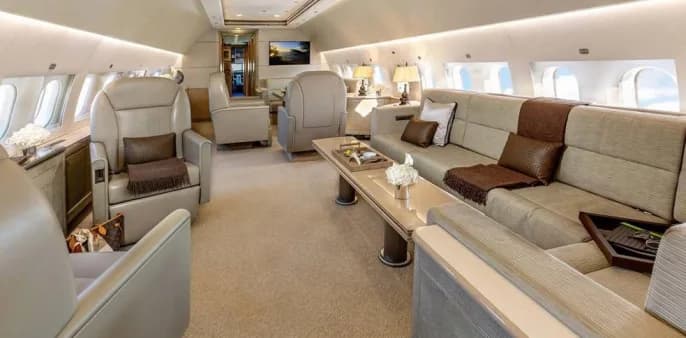 Luxurious aircraft interior with seating, tables, and a television.