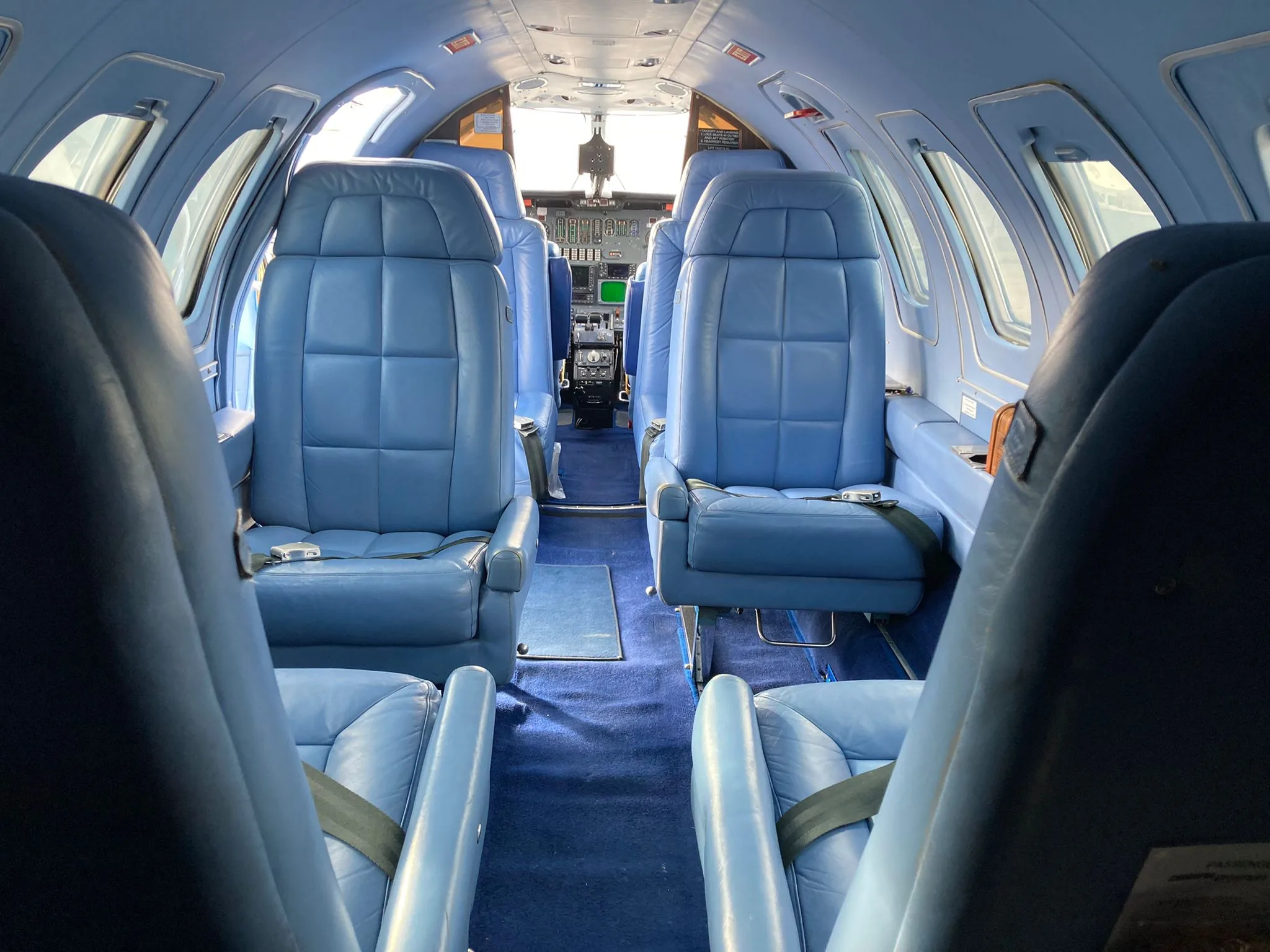Interior of the aircraft with blue leather seats and a view towards the cockpit.